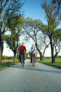 一对夫妇在匈牙利布达佩斯巴拉顿湖绿树成荫的自行车道上骑车