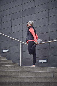 成熟女性在城市训练在楼梯上伸展双腿