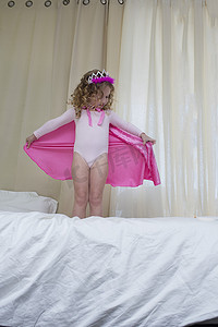 皇室摄影照片_年轻女孩装扮成公主站在床上