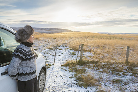 冰岛成熟女子坐在车旁欣赏田野美景