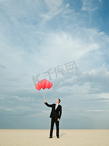 社会主义红色摄影照片_一位商人手里拿着一堆红色气球