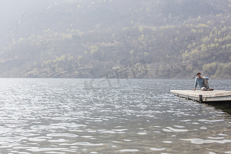 一名年轻人在意大利皮埃蒙特韦尔巴尼亚梅尔戈佐湖码头上用智能手机聊天