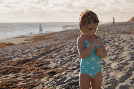 石凯摄影照片_女孩在海滩上检查棍子美国佛罗里达州朱庇特岛吹石保护区