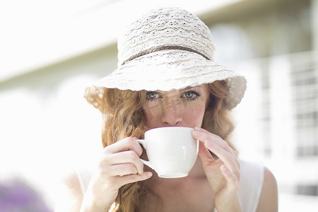 年轻女子在路边咖啡馆用咖啡杯喝咖啡的肖像