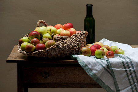 苹果开摄影照片_餐桌上有一篮子苹果和葡萄酒