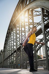 站立的男子摄影照片_德国巴伐利亚州慕尼黑桥上伸展腿的男子