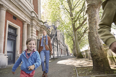 建筑外墙摄影照片_男孩和母亲一起在街上奔跑