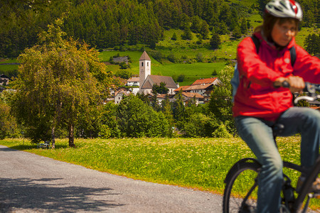 在意大利南蒂罗尔的山谷一名老年妇女在村里的小路上骑自行车