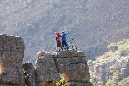 战胜困难摄影照片_山地自行车情侣在岩层上庆祝