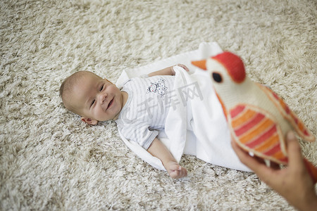 童装上新摄影照片_快乐的男婴看着玩具鸟