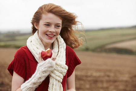 十几岁的女孩在田里吃苹果