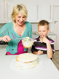 老年妇女和男孩装饰蛋糕