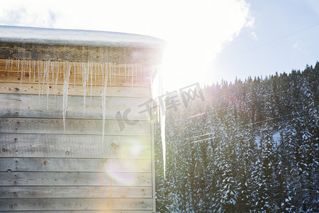 木屋屋顶上阳光普照的冰柱