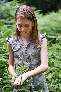 女孩脚趾摄影照片_十几岁的女孩在森林里摸蕨菜