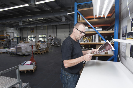 荷兰角摄影照片_印刷车间工作人员检查印刷品质量