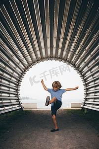 男孩在波纹隧道里手臂张开腿抬起