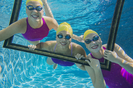 三名女游泳运动员在水下透过镜框看