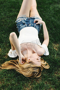 波士顿咨询集团摄影照片_年轻女子躺在草地上抚摸着头发