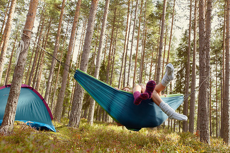 斜上摄影照片_在露营地的吊床上放松的妇女