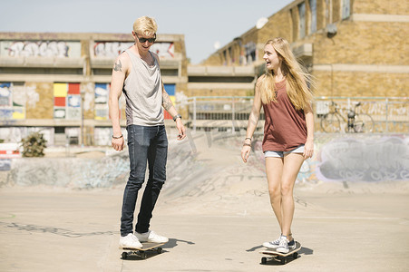 年轻的男女滑板朋友在滑板公园滑板
