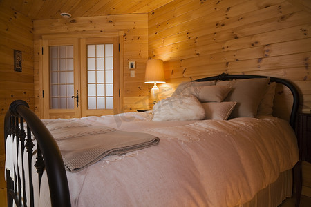 主卧的大床配有铸铁床头板和踏板位于楼上的一个小木屋风格的木屋内