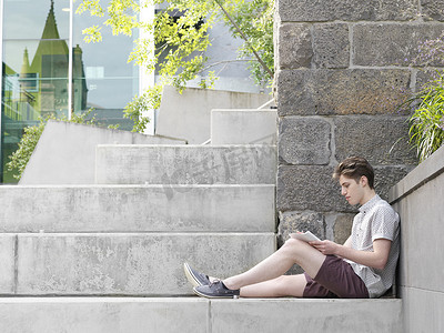 青年大学习摄影照片_年轻人坐在台阶上在户外在记事本上写字