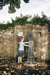 男孩使用户外饮水机的侧视路易诺市伦巴第意大利