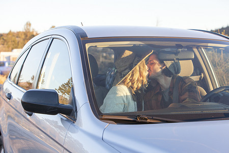 透过挡风玻璃观看年轻情侣在车内接吻