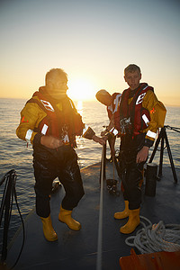 三名男子在海上举着救生艇栏杆的肖像