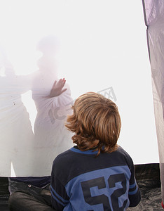 男孩看着帐篷里的影子