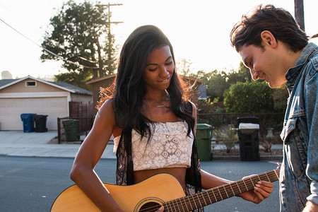 年轻夫妇在户外年轻女子弹吉他