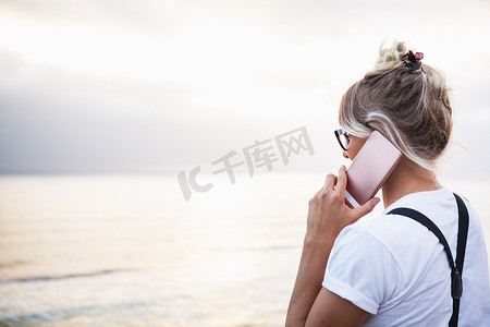 当代文化摄影照片_美国加利福尼亚州恩西尼塔斯海边妇女在智能手机上打电话