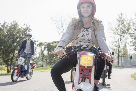 聚会摄影照片_一群朋友骑着轻便摩托车沿路行驶年轻的女骑手在前台