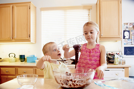 搅拌碗摄影照片_兄弟姐妹在搅拌碗里融化巧克力