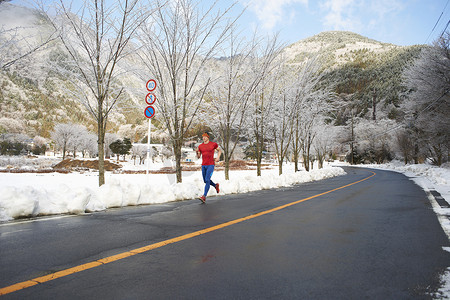 乡村大道摄影照片_日本富士山川口湖冬季在路上跑步的男子