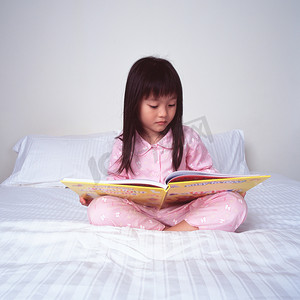 黄狮鱼摄影照片_年轻女孩躺在床上看书