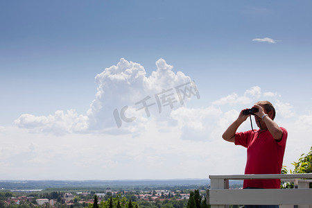 投用摄影照片_上了年纪的男子在屋顶上用望远镜