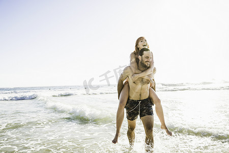 南非开普敦一名男子穿着游泳短裤背着女友在海上
