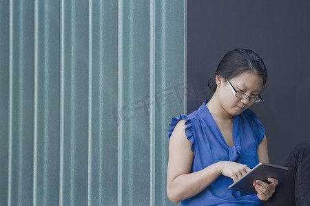 墙前的年轻女子使用数字平板电脑上的触摸屏