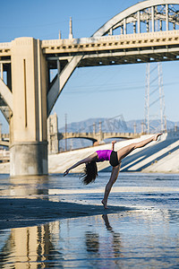 美国洛杉矶加利福尼亚州桥前舞者的侧视抬起腿向后弯下腰