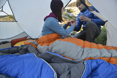 名柯摄影照片_爱达荷州塞尔柯克山一名男子在帐篷里给女友递咖啡