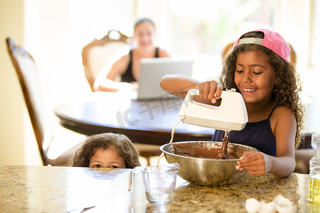 姐妹们在搅拌碗里搅拌巧克力蛋糕微笑着