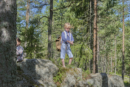 在森林里的岩石上穿着复古服装的男孩