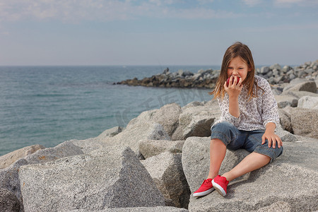 女孩在岩石海滩上吃苹果