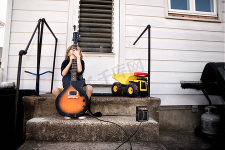 电人玩具摄影照片_害羞的男孩和他的吉他