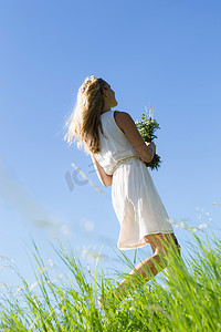 在高高的草丛中拿着花束的女人