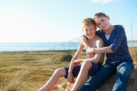 男孩和十几岁的女孩坐在海滩上