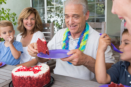 老年人在与家人的聚会上提供一片生日蛋糕