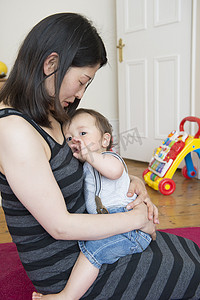 成熟的母亲坐在地板上儿子抱在膝上