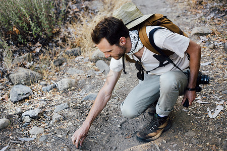 美国加利福尼亚州马里布峡谷徒步旅行者蹲着捡石头